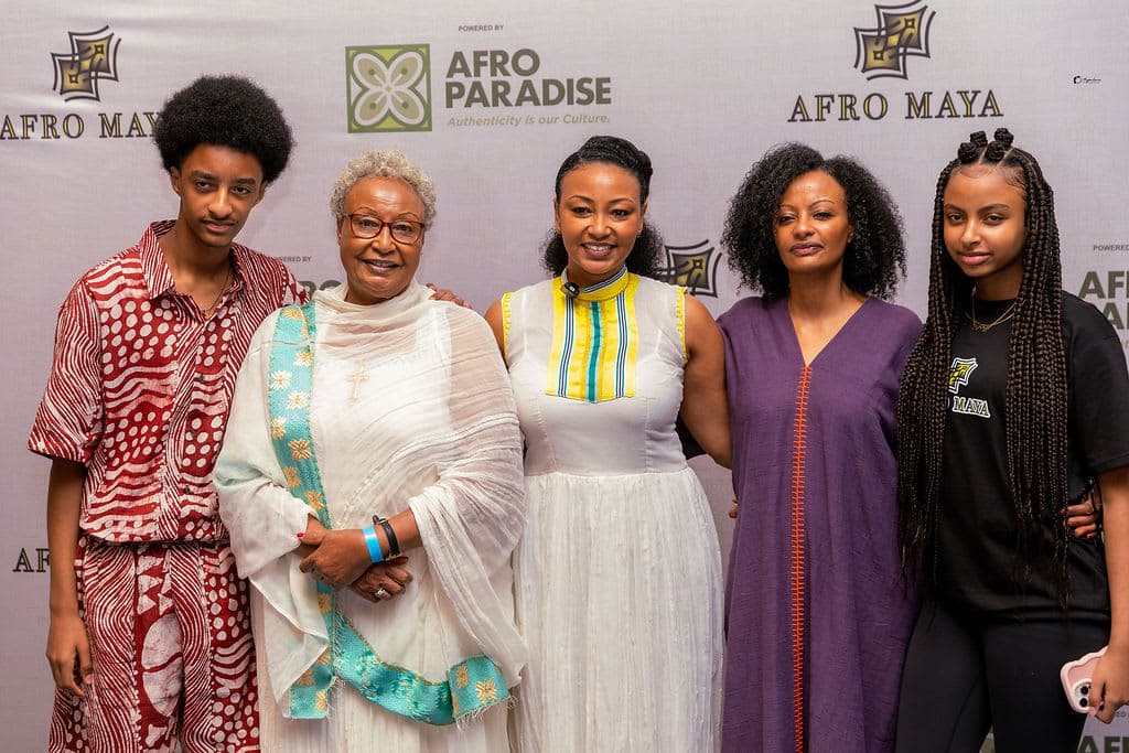 AfroMaya's founding team in front of the AfroMaya–AfroParadise photography backdrop