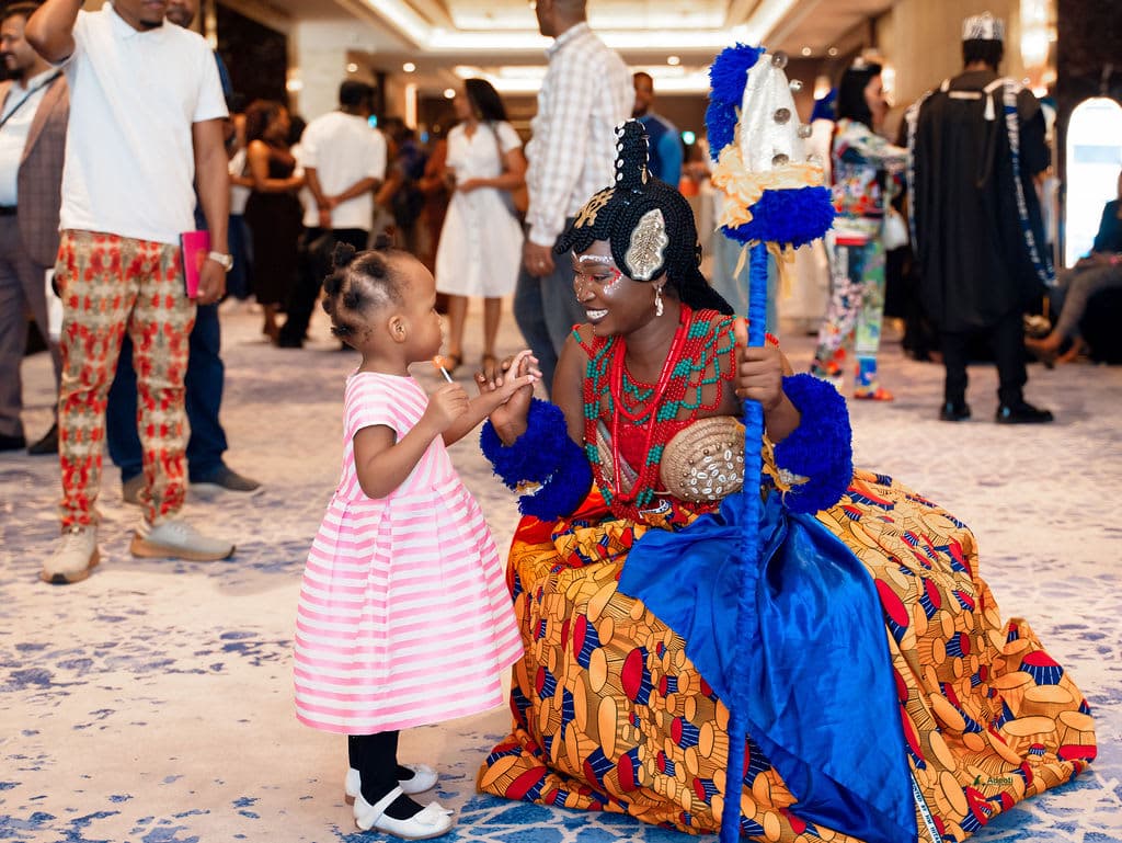 A performer in traditional dress greets a young guest